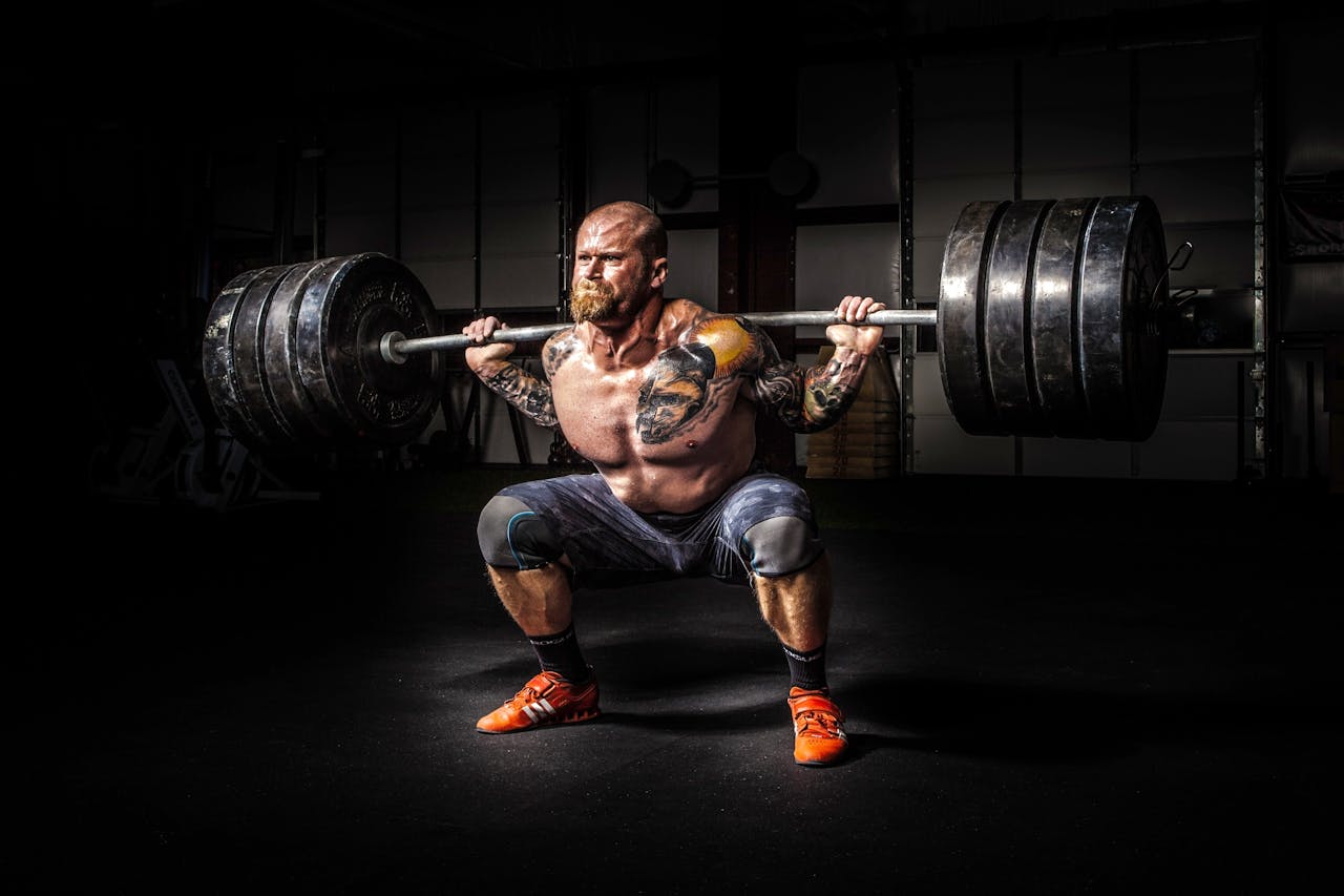 Muscular man lifting heavy weights during an intense squat session inside a gym.